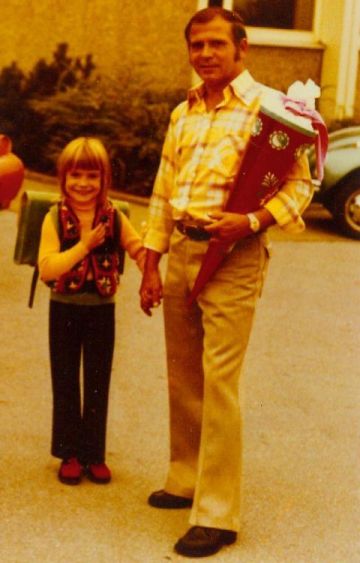 Meine Einschulung mit Papa, mit grünen Tornister und eine lila gepunkte Schultüte, die mein Vater trägt.